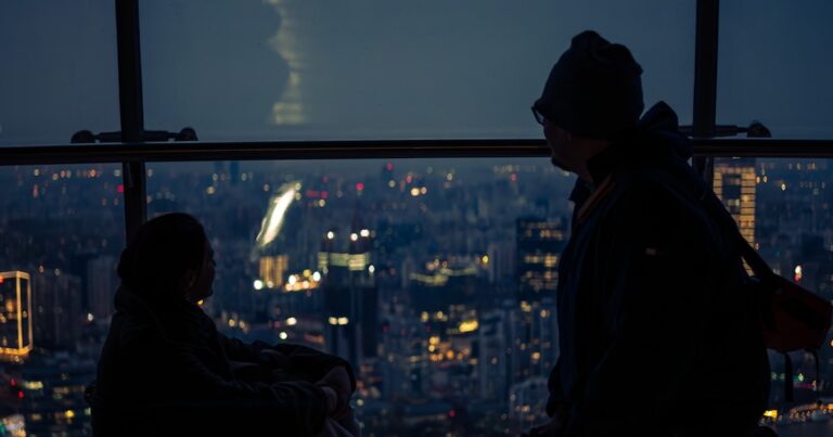 Silhouettes de deux personnes sur la ligne d’horizon d’une ville la nuit