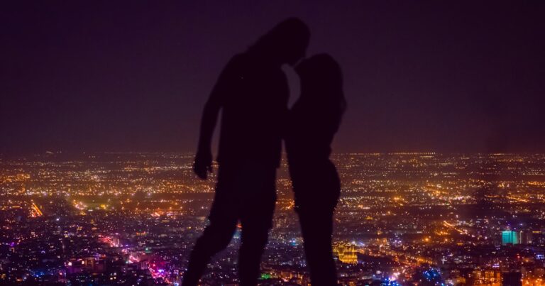 Deux personnes debout au sommet d’une colline la nuit
